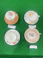 Top view of four tea cup and saucer sets displayed on green surface
