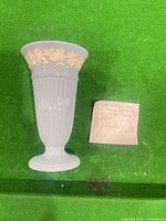 Full view of light blue jasperware vase standing upright on green background