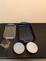 All five items laid out: blue baking dish, clear loaf dish, measuring cup, two white bowls