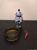 Ashtray, porcelain jar with lid, red horn keychain displayed together