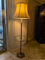 Full view of brass floor lamp showing shade, column, glass table, and base