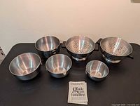 All six stainless pieces and booklet displayed