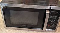 Front view of countertop microwave oven showing stainless frame, black glass door, overall exterior condition