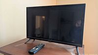 Front view of Insignia 24" LED HDTV on stand with remote placed in front