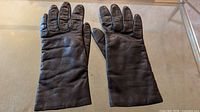 Pair of dark brown leather gloves laid flat palms down