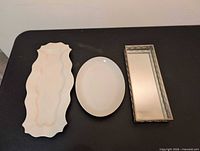 Three trays laid out: scalloped ceramic, oval ceramic, rectangular mirrored