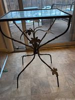 Full view of table showing glass top, metal frame and leaf details