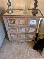 Front view of mirrored three-drawer cabinet showing mirrored panels and knobs