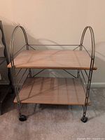 Front angle of rolling TV stand showing two shelves, metal frame, casters