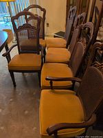 Six wood dining chairs lined up showing two with arms and four without, cane backs and velvet seats visible