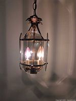 Close view of illuminated brass and glass pendant showing two candelabra bulbs