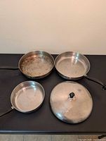 Three frying pans and one lid top view