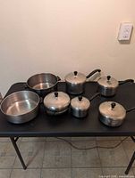 Group shot of six Farberware pots with lids and insert on table