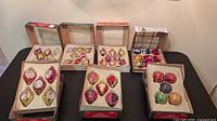 Overall view of nine boxes of vintage glass ornaments on table