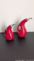 Two red ceramic dispensers standing side by side