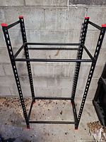 Full view of black steel rack showing four uprights, horizontal bars, base frame