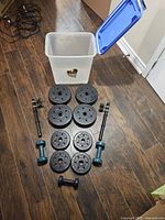 Complete set laid out with plates, bars, fixed dumbbells and bin
