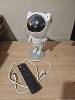 Astronaut projector with remote and USB cable on tabletop