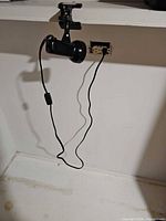 Full view of black clamp light attached to shelf showing cord and inline switch