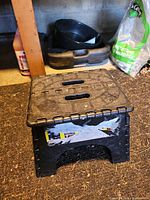 Stool folded out, front view showing handle slots and tape residue