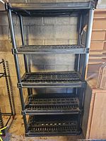 Full view of 5-shelf black plastic shelving unit against wall