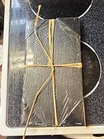 Two stacked black slate boards wrapped in plastic and tied with raffia
