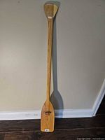 Full view of the 4 ft wooden canoe paddle leaning against wall