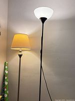 Both floor lamps standing against wall showing shades and poles