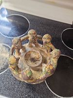 Top view of terracotta figurine candle holder showing central candle recess and six figures