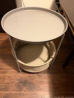 Side table assembled showing gray tray top and beige fabric basket