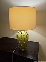 Front view of lime green ceramic lamp illuminated with drum shade