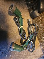 Two green outdoor light socket stakes with cords and plugs visible on floor