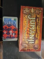 Jumanji game box beside chess tin