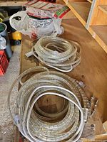 Coiled LED rope light sections with attached power cords and bag of mounting clips on workbench