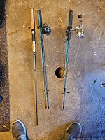 Both two-piece fishing rods with attached reels laid out on floor