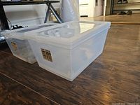 two translucent storage boxes stacked on floor showing size and clarity
