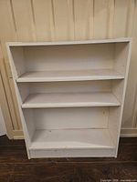 Front view of white laminated particleboard bookcase showing two adjustable shelves and base