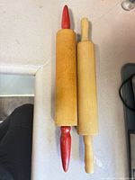 Two wood rolling pins side by side on countertop, showing handle styles and overall condition