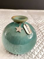 Front view of spherical teal vase with attached charms