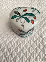 Top view showing green leaves, red berries design on heart-shaped lid