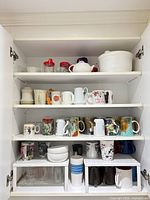 Cabinet view showing mugs, teapot, plastic cups and casserole dish