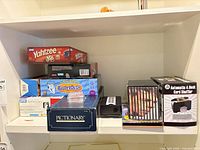 Shelf view showing Yahtzee, Balderdash, Pictionary, card shuffler box and Bob Dylan CD box