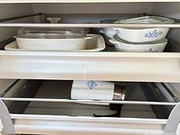 Drawer view showing CorningWare casseroles and lids on shelf