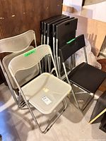 Stack of white and black plastic folding chairs with metal frames