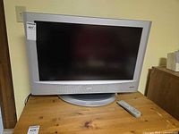 Front view of 32-inch JVC LCD TV on stand with remote