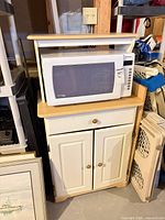 Full view of cabinet with microwave staged on upper shelf