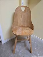 Front view showing curved plywood back with cut-out, round seat and legs