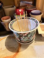 Assorted planters showing large floral pot with saucer and surrounding smaller pots