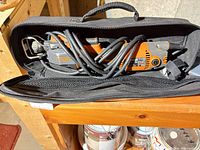 Multi-tool coiled in zippered case showing tool body and cord