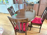 Table with three chairs visible, dark brown finish, red cushions